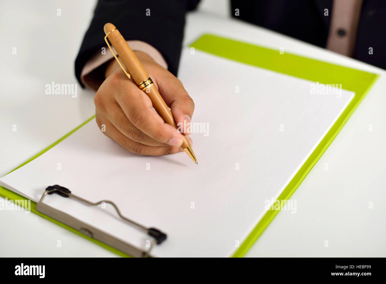 Business man writing on clipboard on the desk Stock Photo - Alamy
