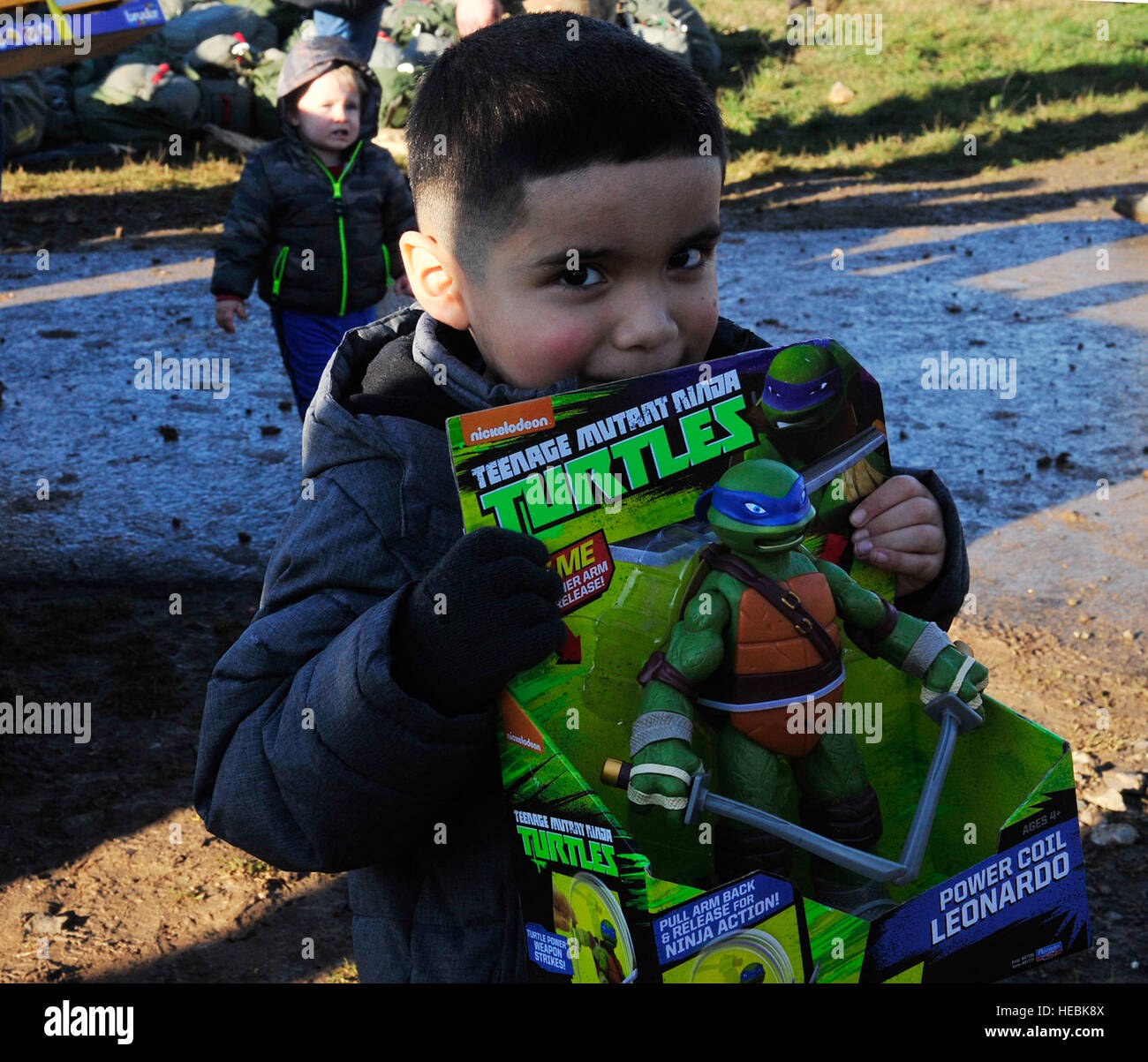 Julian Obregon, son of Tech. Sgt. Jose Obregon, 435th Contingency Response Group independent duty medical technician, shows off his toy from Santa Claus during the International Jump Week toy drop Dec. 7, 2015, at Alzey Drop Zone, Germany. The toy drop is a yearly event in which toys are dropped to children in the community during the holiday season. (U.S. Air Force photo/Airman 1st Class Larissa Greatwood) Stock Photo