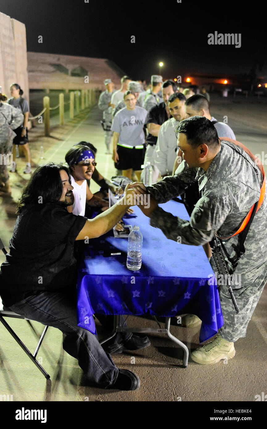A U.S. Soldier shakes the hand of Ringo, drummer for the Grammy Award winning rock band 'Los Lonely Boys,' as other service members wait in line for autographs after a music concert featuring this Texas based trio at Contingency Operating Base Speicher, in northern Iraq, Sept. 4. Stock Photo