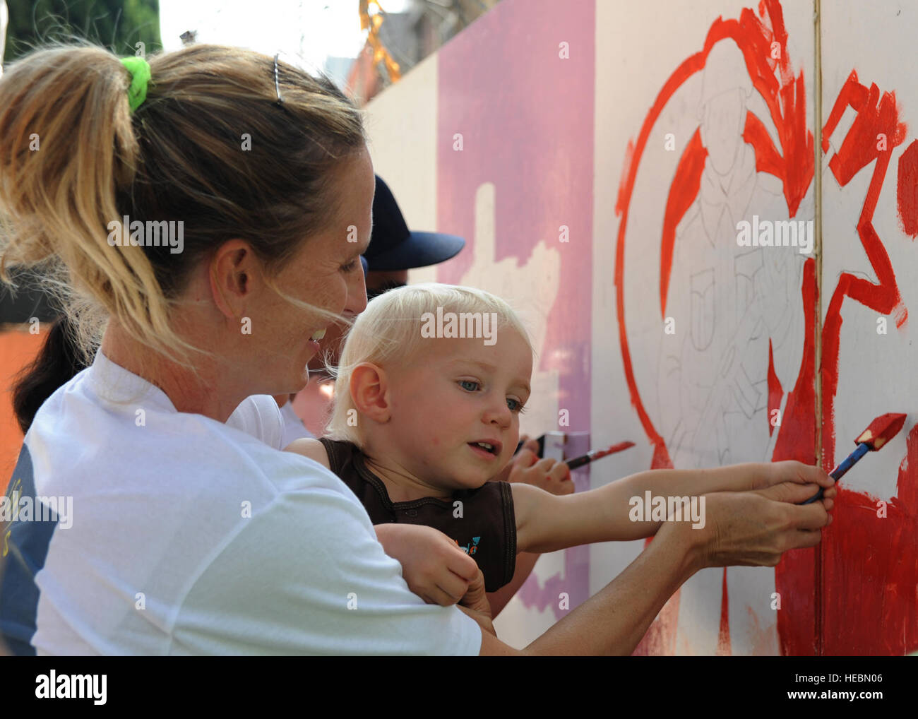 Linne Gherdovich and son Hudson, paint a mural of a Turkish soldier at the Kazim Karabekir School for Autism, June 9, 2014, Adana, Turkey. Gherdovich is a coordinator with the organization Love Impact Give Help Teach Serve, or LIGHTS located at Incirlik Air Base, Turkey. The group of active duty members, civilians and dependents of all ages focuses on helping the community with simple art projects at special needs schools around Adana. (U.S. Air Force photo by Staff Sgt. Veronica Pierce/Released) Stock Photo