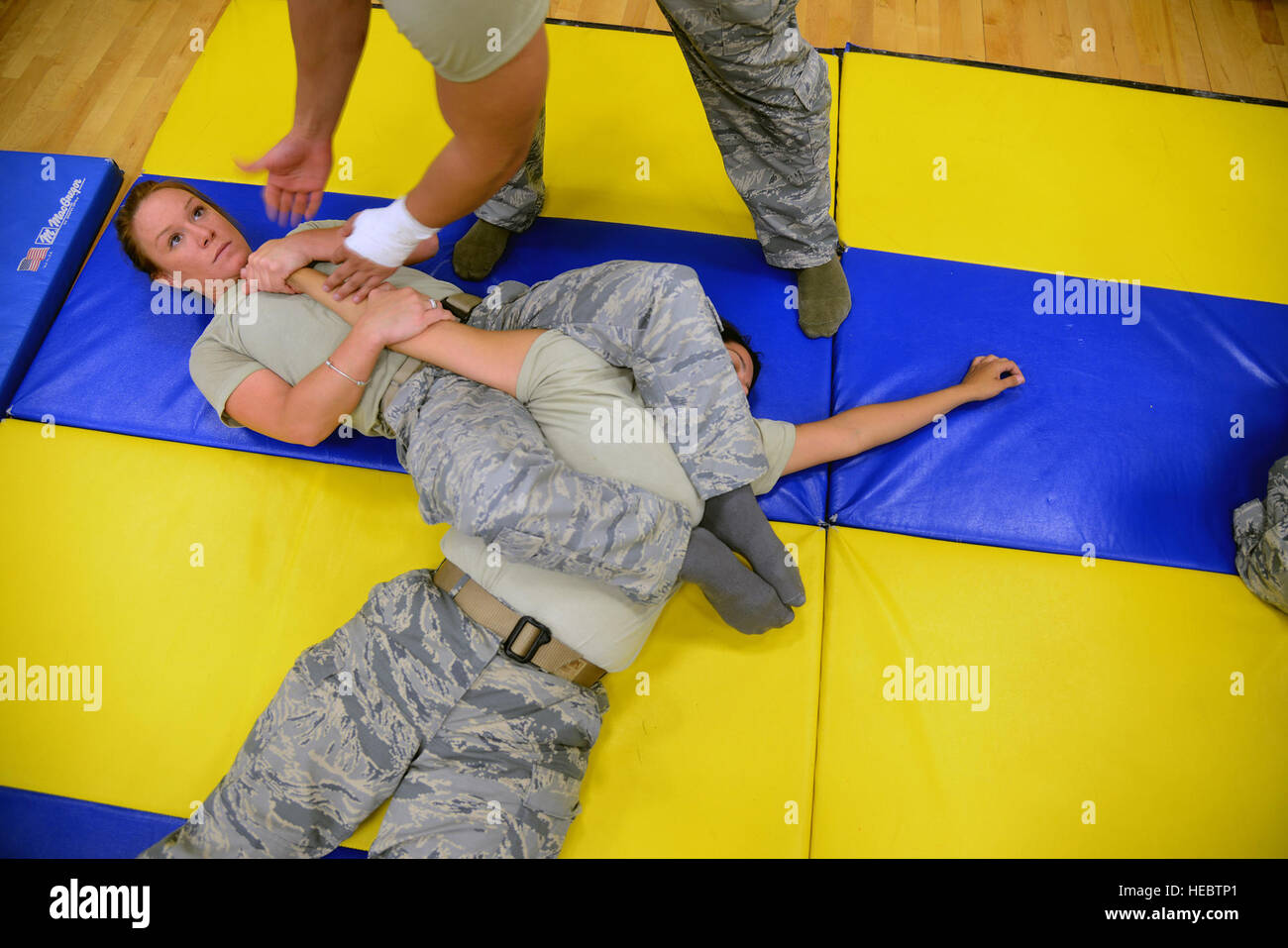 Senior Airman Melissa Goodhile, 47th Security Forces Squadron military working dog handler, finalizes an 'arm bar' on Staff Sgt. Lacy Ruiz, 47th SFS combat arms instructor, in Losano Fitness Center on Laughlin Air Force Base, Texas, July 10, 2015. The straight arm bar is a six-step, joint lock process designed to damage the elbow by trapping the bicep and triceps region between the submissor's leg. (U.S. Air Force photo by Tech Sgt. Steven R. Doty/Released) Stock Photo