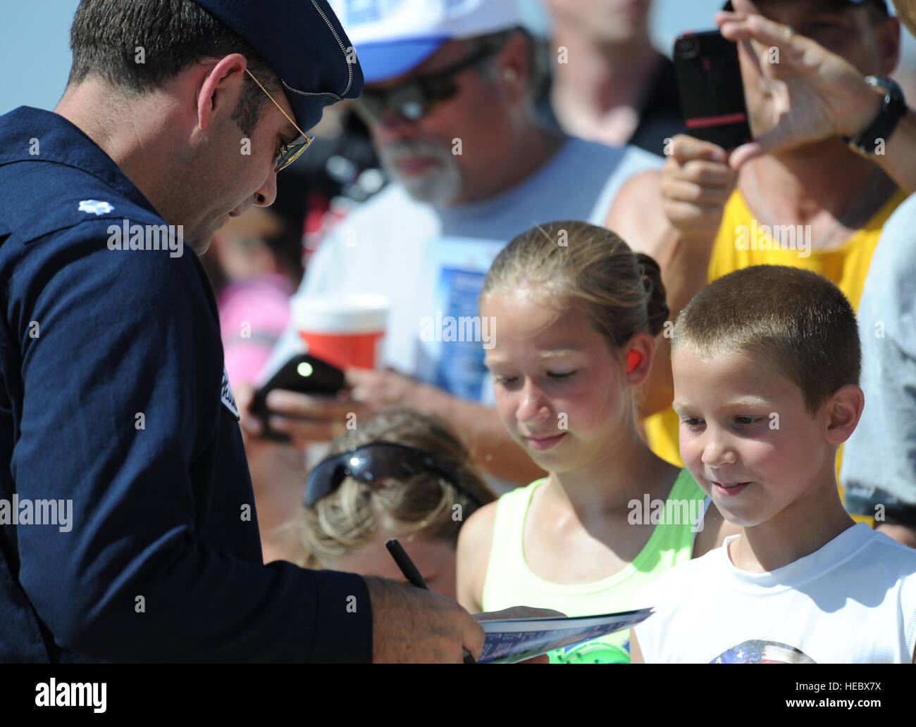 Lt. Col. Greg Moseley, Thunderbird 1, commander/leader, autographs a brochure as a young fan looks on with admiration following the performance at the Star Spangled Salute Air Show, Tinker Air Force Base, Okla., June 22, 2014. (U.S. Air Force Photo/Master Sgt. Stan Parker) Stock Photo