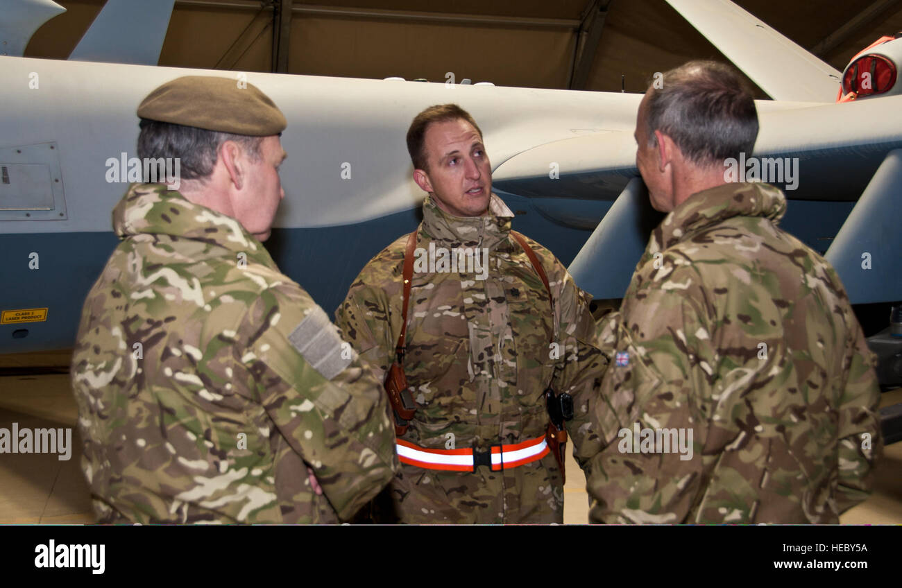 A U.S. Airman, center, with the 62nd Expeditionary Reconnaissance Squadron (ERS), speaks to Royal Air Force (RAF) Gen. Nicholas Houghton, left, the Vice Chief of the Defense Staff of the British armed forces, and RAF Air Marshal Steve Hillier about the squadron?s assigned MQ-9 Reaper unmanned aerial vehicles during Houghton?s visit Jan. 23, 2012, at Kandahar Airfield, Afghanistan. Several RAF members were attached to the 62nd ERS and flew a British MQ-9 during reconnaissance operations. (U.S. Air Force photo by SSgt David Carbajal/Released) Stock Photo