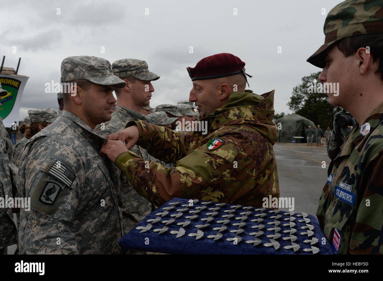 Corporal Mauro Alasia, Italian Army paratrooper, distributes Italian jump wings during Operation Toy Drop, Fort Bragg, N.C., Dec. 7, 2013. The 16th Annual Randy Oler Operation Toy Drop, hosted by the U.S. Army Civil Affairs & Psychological Operation Command (Airborne), is the largest combined airborne operation in the world where Fort Bragg's paratroopers and allied jumpmasters donate toys to be distributed to children's homes and social service agencies across the local community. (U.S. Air Force photo by Senior Airman Kenneth W. Norman / Released) Stock Photo