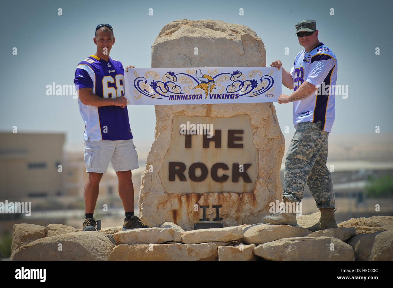 In anticipation of the upcoming NFL regular season kickoff, Minnesota Vikings fans and deployed U.S. soldiers Chief Warrant Officer 4 Joel Gordon and Spc. Lance Nielsen pose for a photo at the 386th Air Expeditionary Wing's 'Rock' monument proudly wearing their Vikings jerseys, Sunday, Aug. 25, 2013. Gordon, a Dassel, Minn. native, is a C-12 pilot stationed with Detachment 51 at Joint Base Lewis-McChord. He currently lives in Washington state. Nielsen, a St. Paul, Minn., native, is an aviation operations specialist with Detachment 39 at Army Aviation Support Facility Number 1 of the Minnesota  Stock Photo