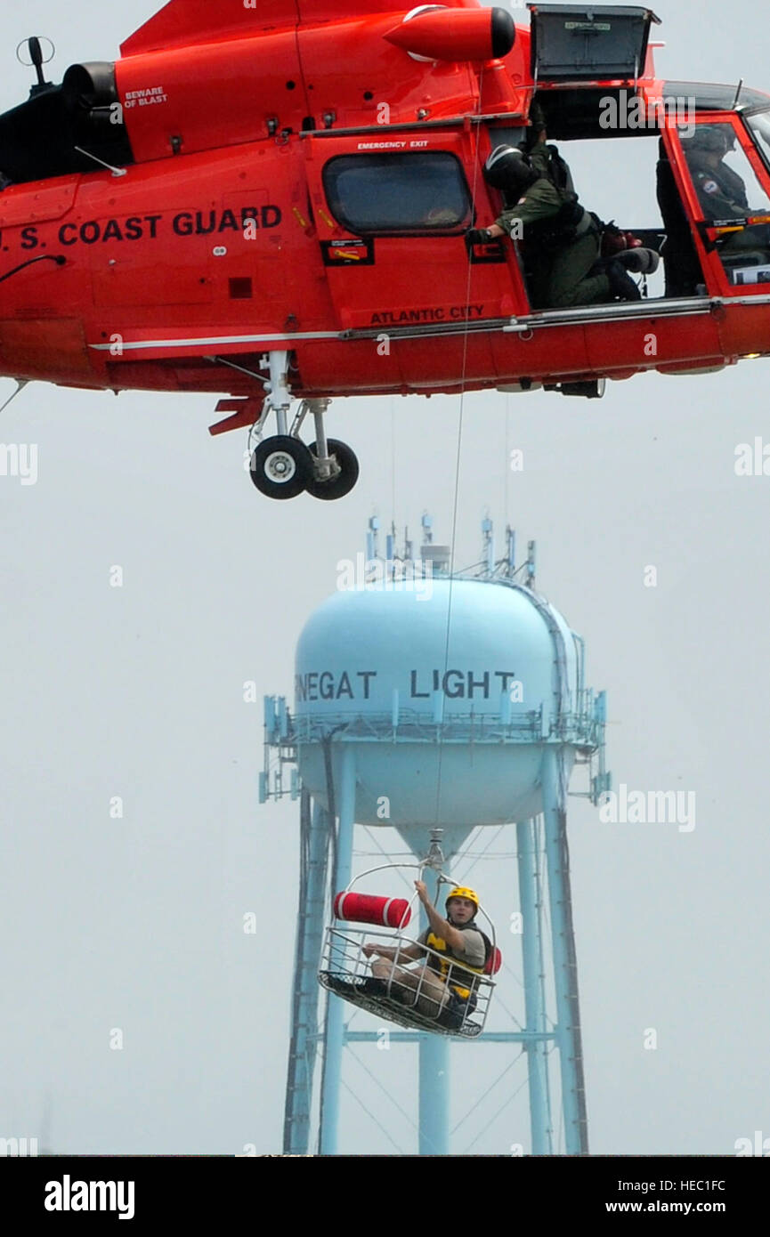 U.S. Air Force Staff Sgt. James Stewart, a public affairs broadcaster with the 621st Contingency Response Wing, holds onto a rescue basket under a Coast Guard H-65 Dolphin helicopter during water survival training in the bay near Coast Guard Station Barnegat Light, N.J., Aug. 18, 2011. Students rehearsed swimming techniques and raft survival skills before a Coast Guard H-65 Dolphin helicopter retrieved each student. (U.S. Air Force photo by Tech. Sgt. Parker Gyokeres/Released) Stock Photo