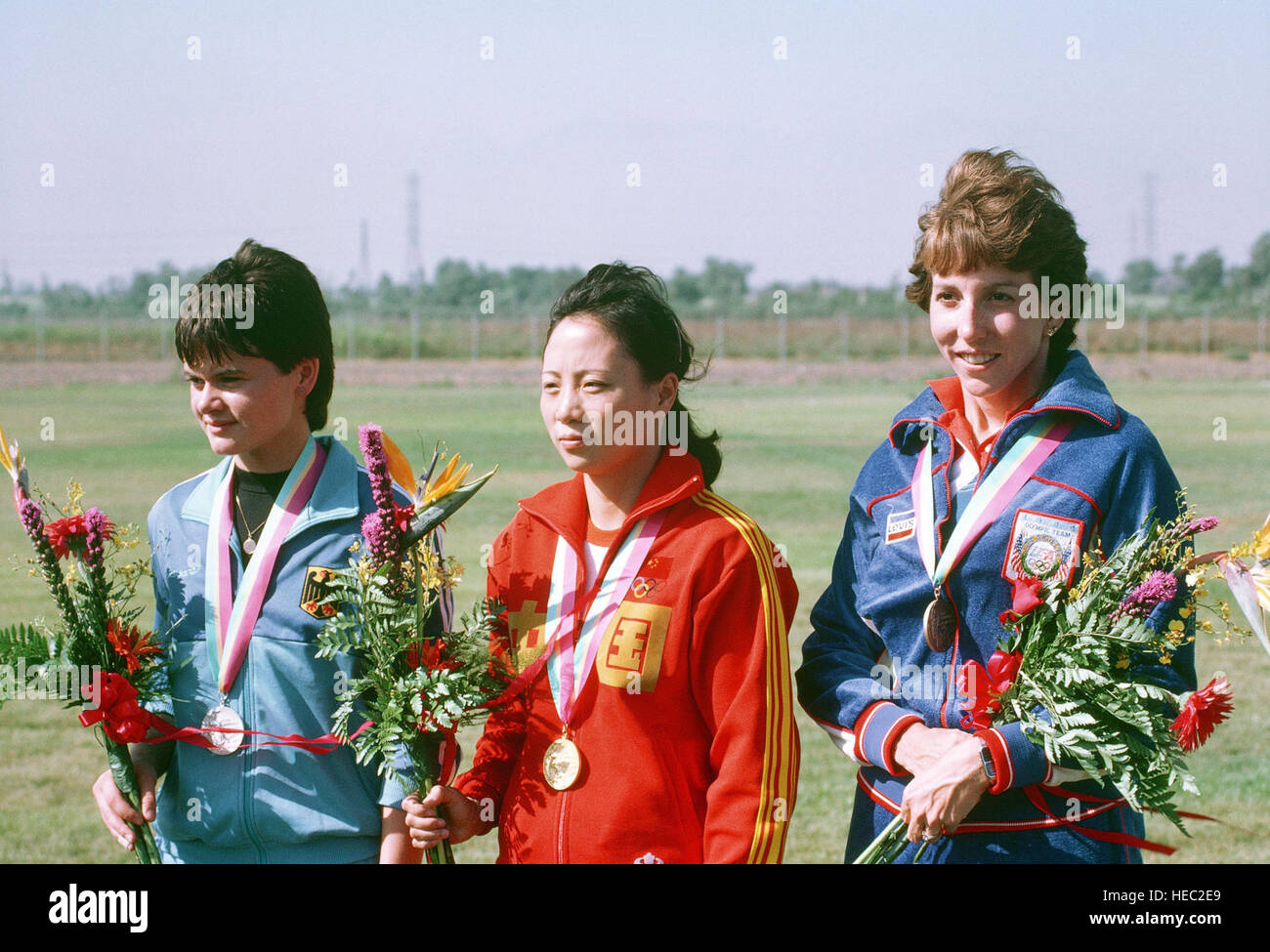 Army Reserve Captain Wanda R. Jewell, right, from Redstone Arsenal, Alabama, stands with gold medalist Wu Xiauxuan of Red China and silver medalist Ulrike Holmwe of West Germany,  after receiving a bronze medal in the small-bore rifle competition at the 1984 Summer Olympics. Stock Photo