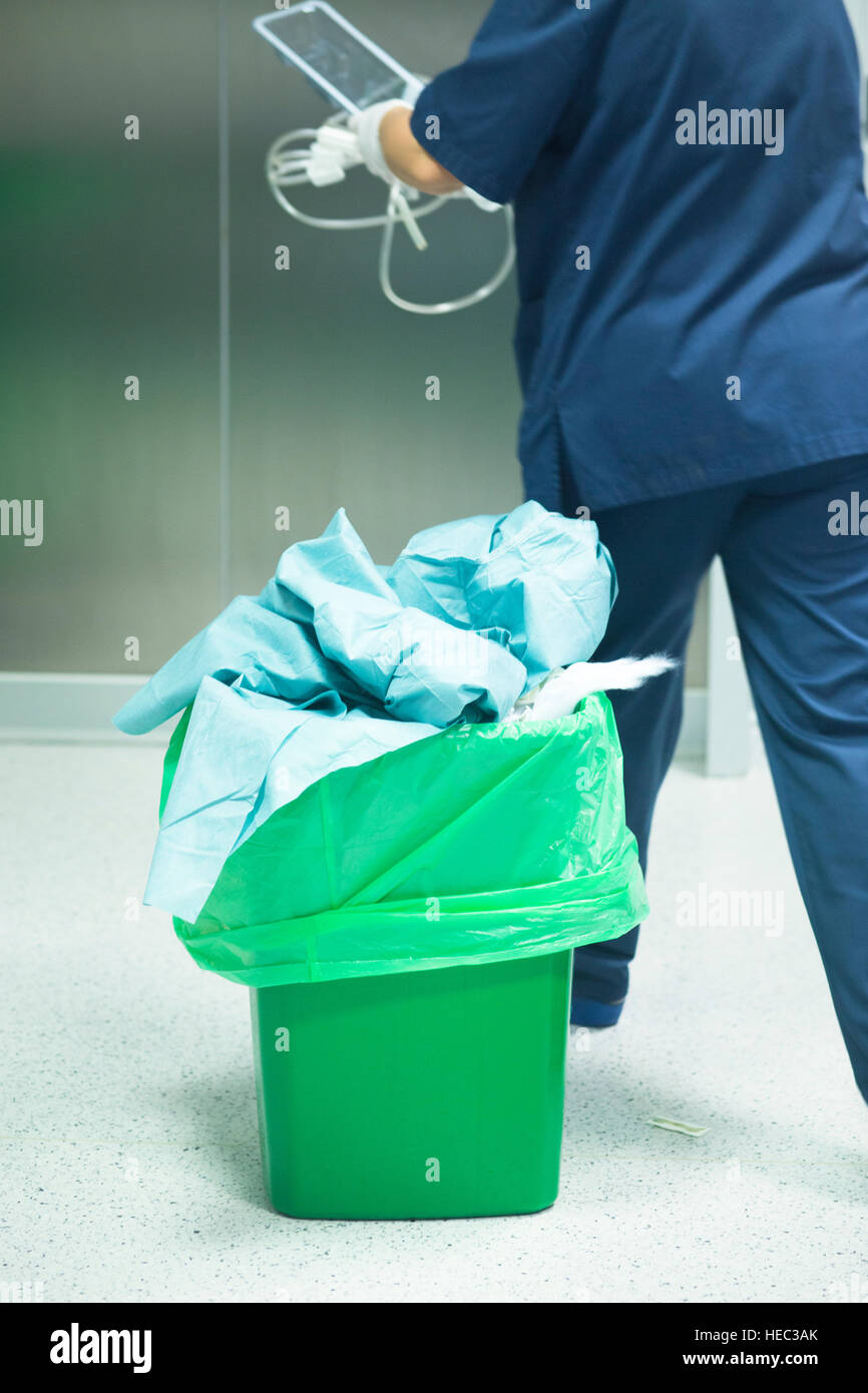 Operating theater surgery trash bin and nurse with green plastic bag