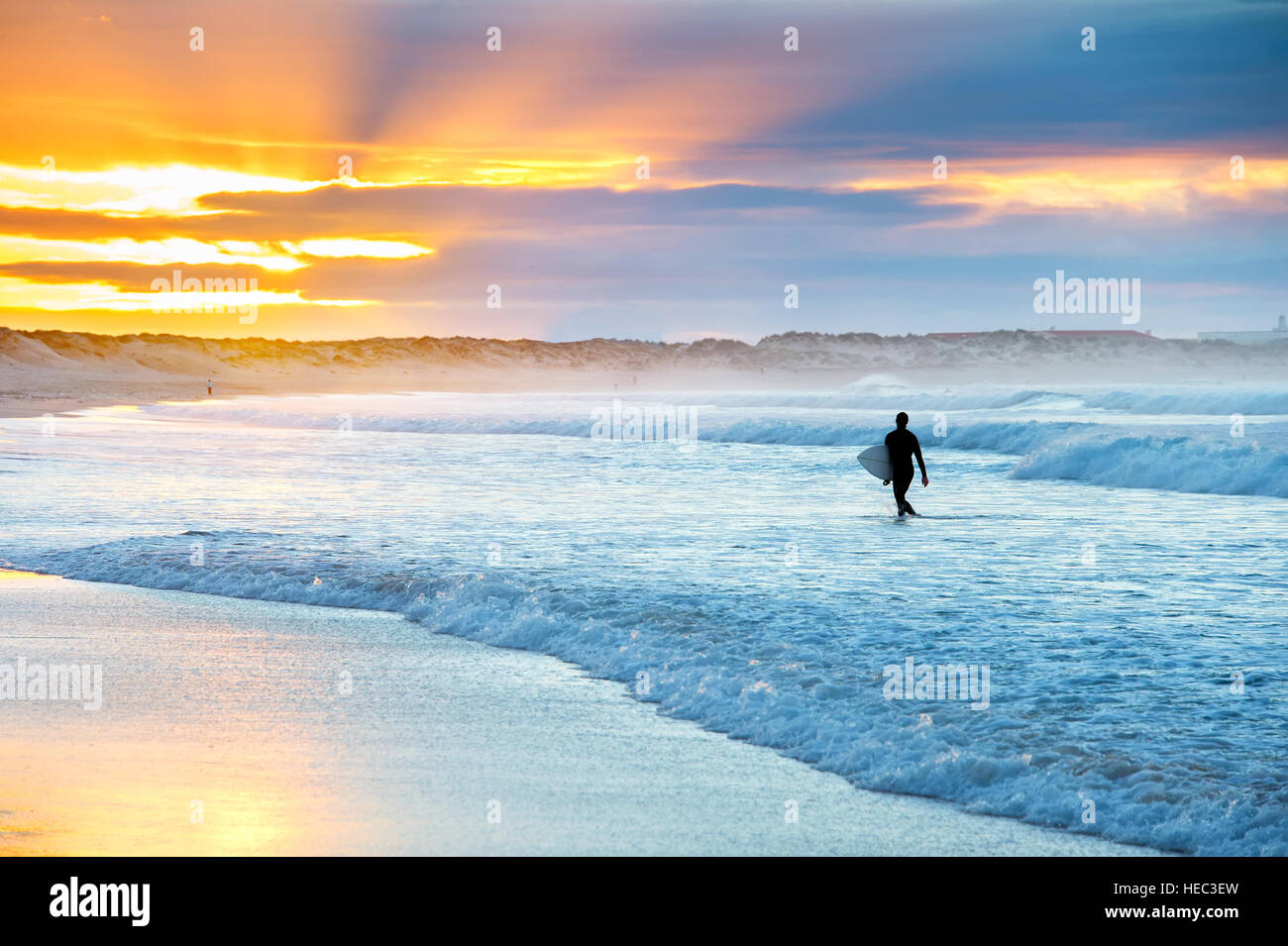 Surfer with surfboard in the ocean at sunset Stock Photo Alamy