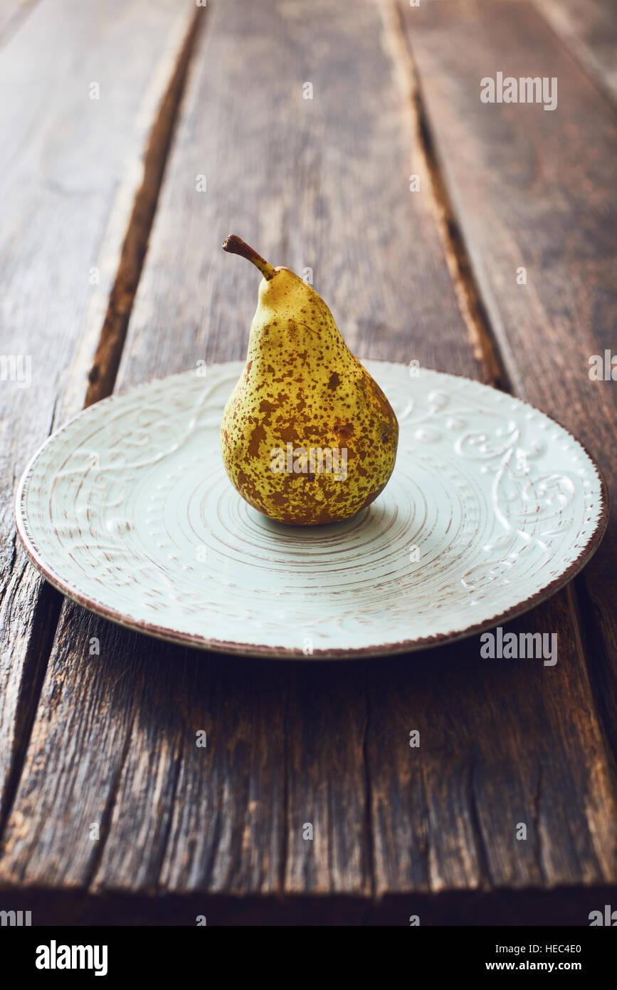 Pear on vintage dish and wooden table Stock Photo