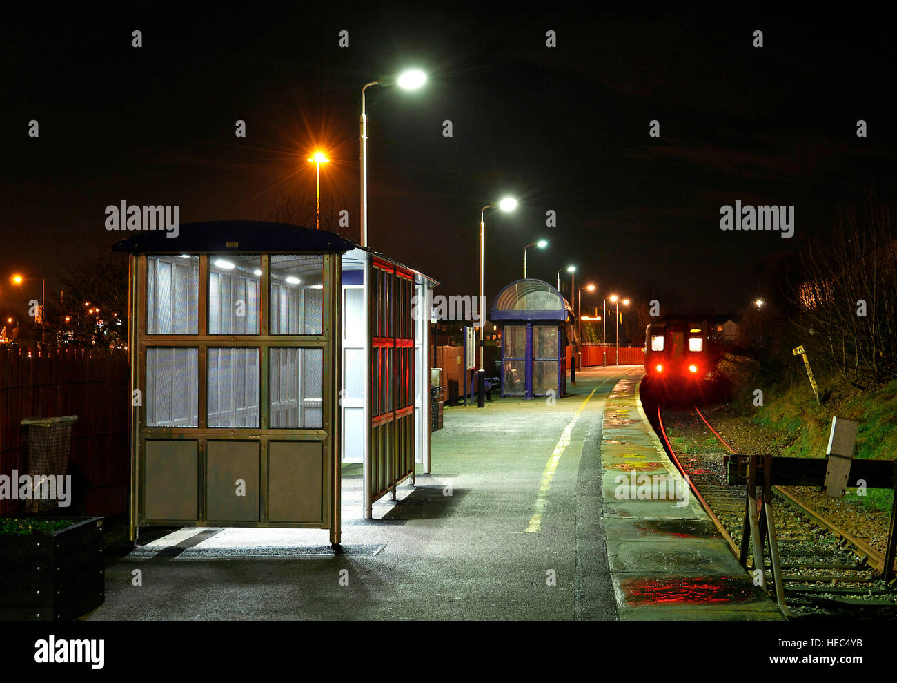 Train departing small railway station at night Stock Photo