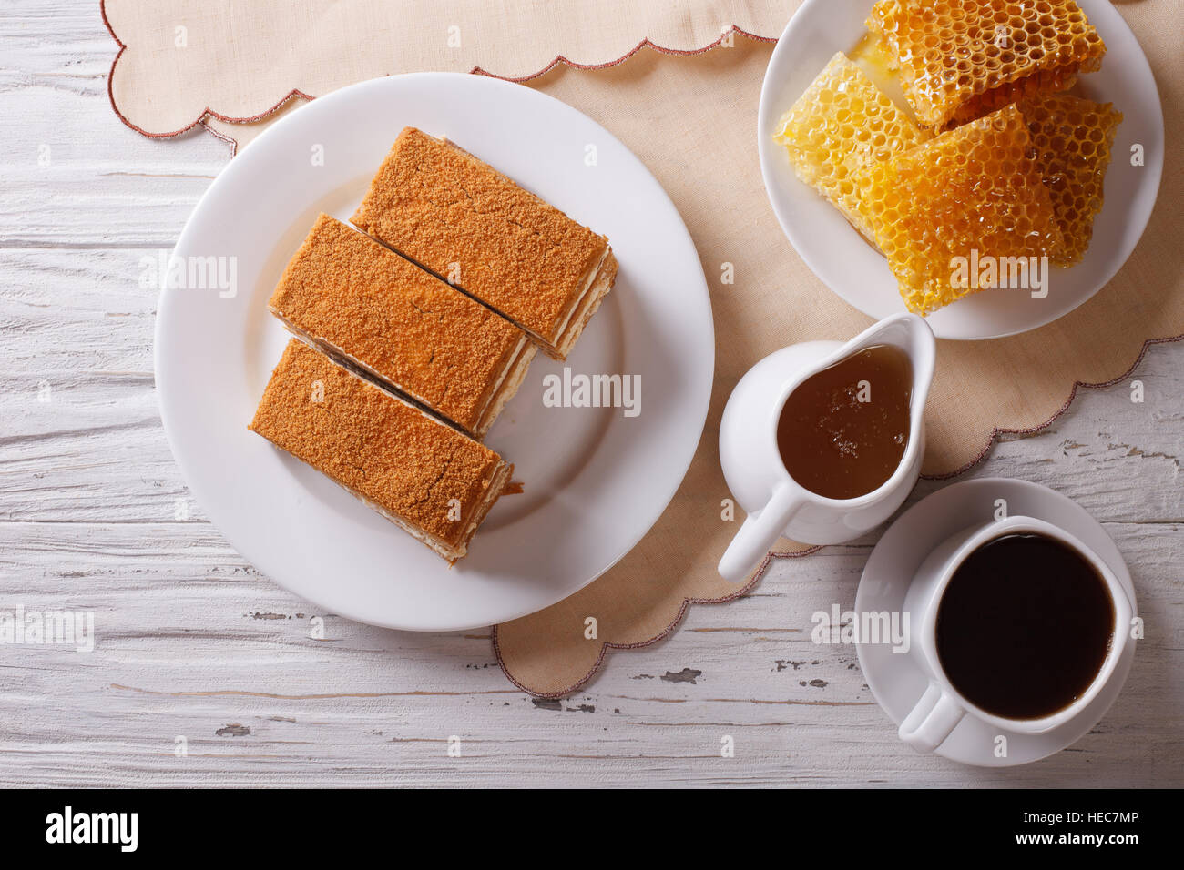Sliced honey cake on a plate, coffee, and a honeycomb. Horizontal top view Stock Photo