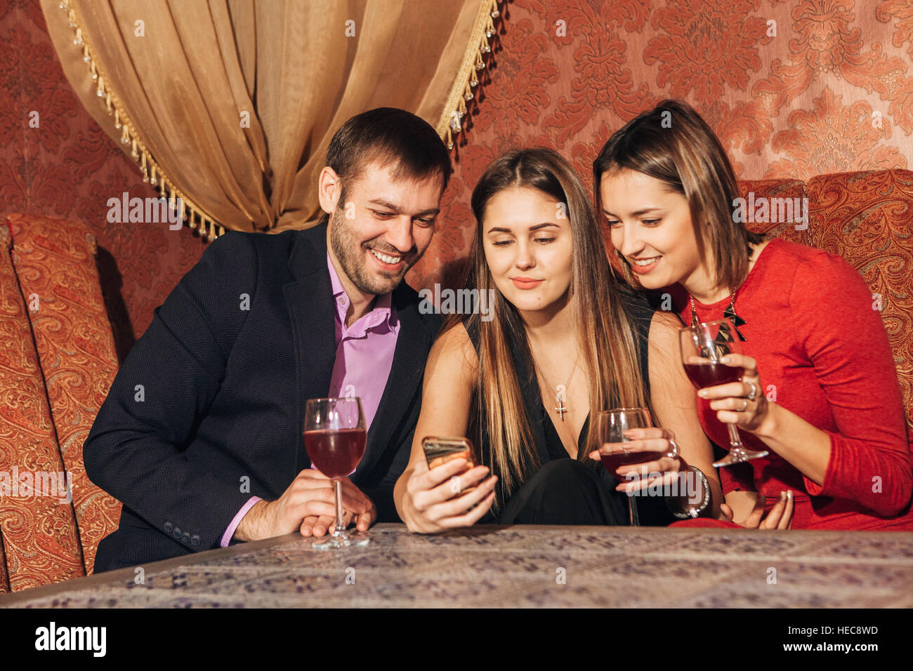 two cute women and a man sitting in  restaurant  use the phone Stock Photo