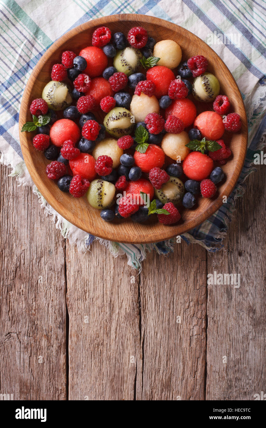 salad of blueberries, raspberries, melon and watermelon in a wooden bowl. vertical top view Stock Photo