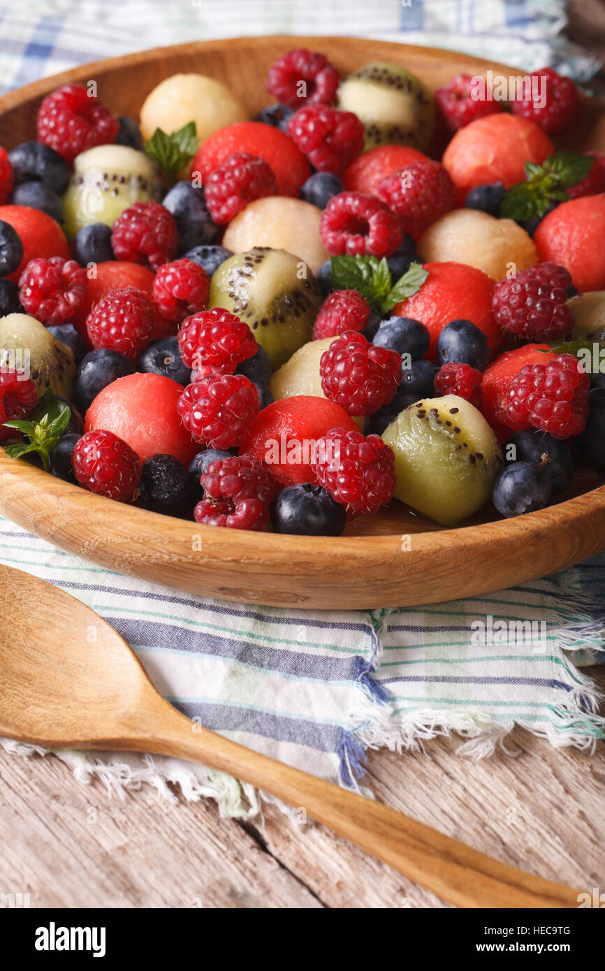 salad of fresh fruits and berries in a wooden bowl closeup. rustic style vertical Stock Photo