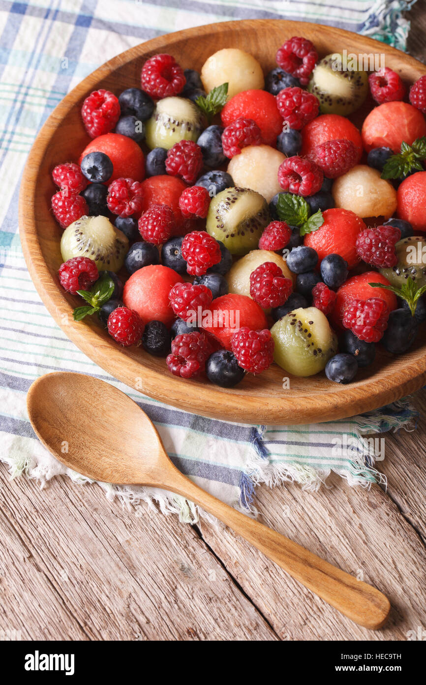 salad of blueberries, raspberries, melon and watermelon in a wooden bowl closeup. rustic style vertical Stock Photo