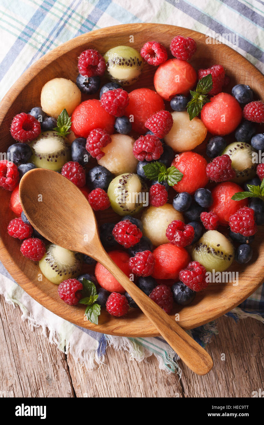 Delicious summer fruit salad in wooden bowl closeup. vertical top view Stock Photo