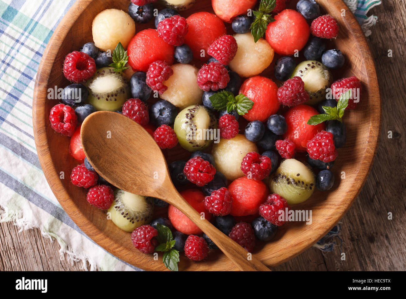 Delicious summer fruit salad in wooden bowl closeup. horizontal view from above Stock Photo