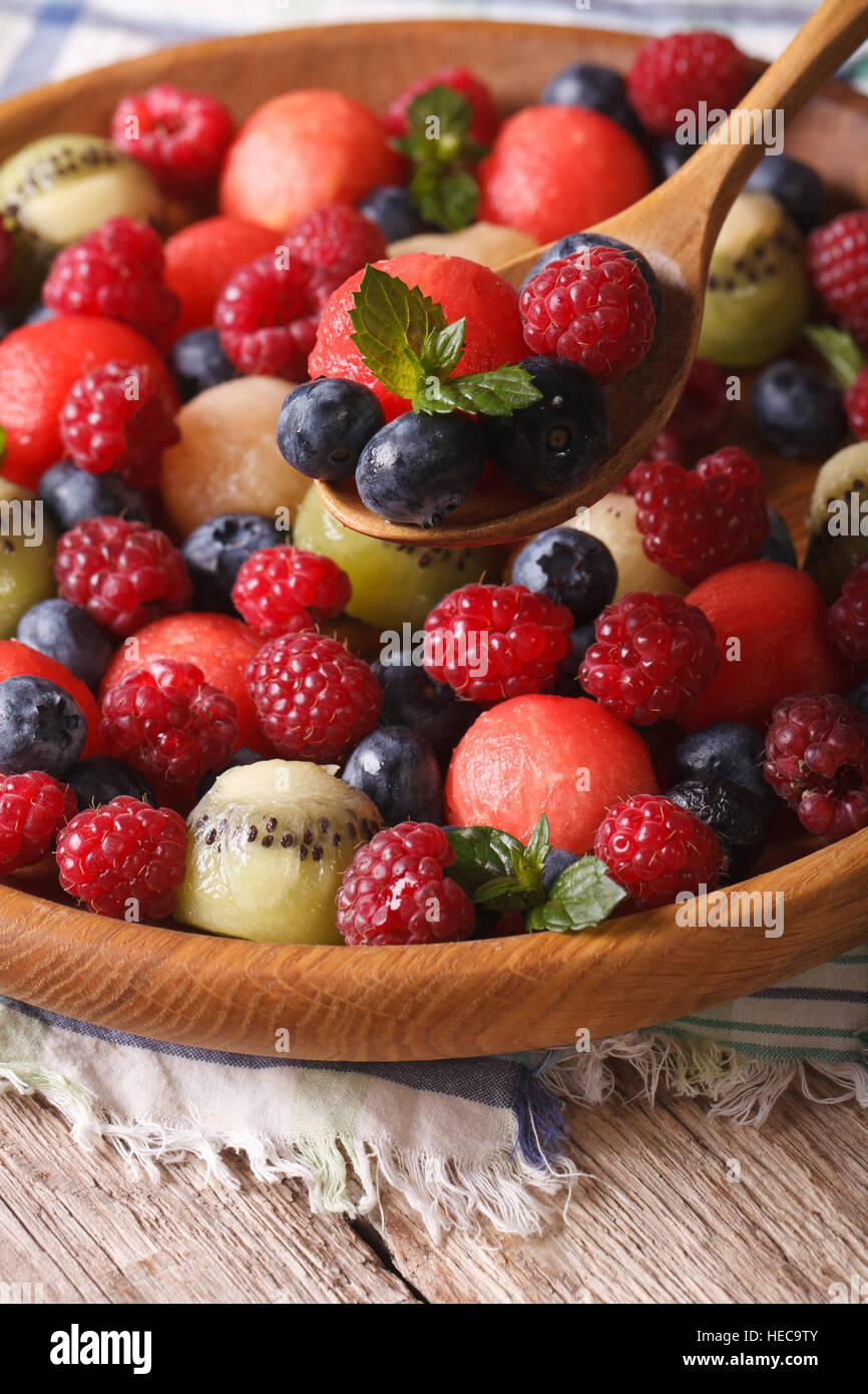 Delicious summer fruit salad in wooden bowl closeup. vertical Stock Photo