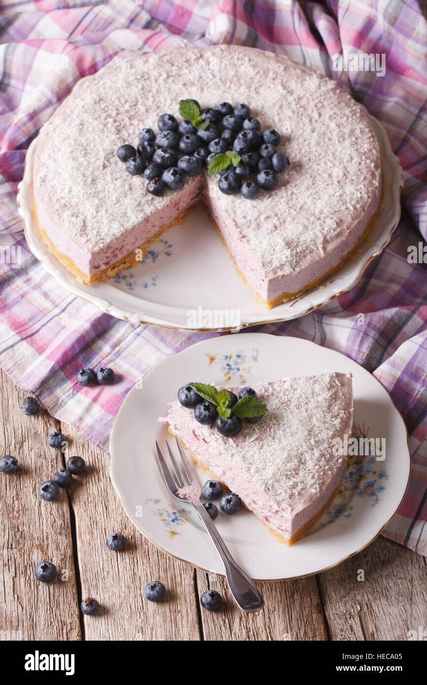 Cut a piece of blueberry cheesecake with fresh berries and coconut close-up on a plate. vertical Stock Photo