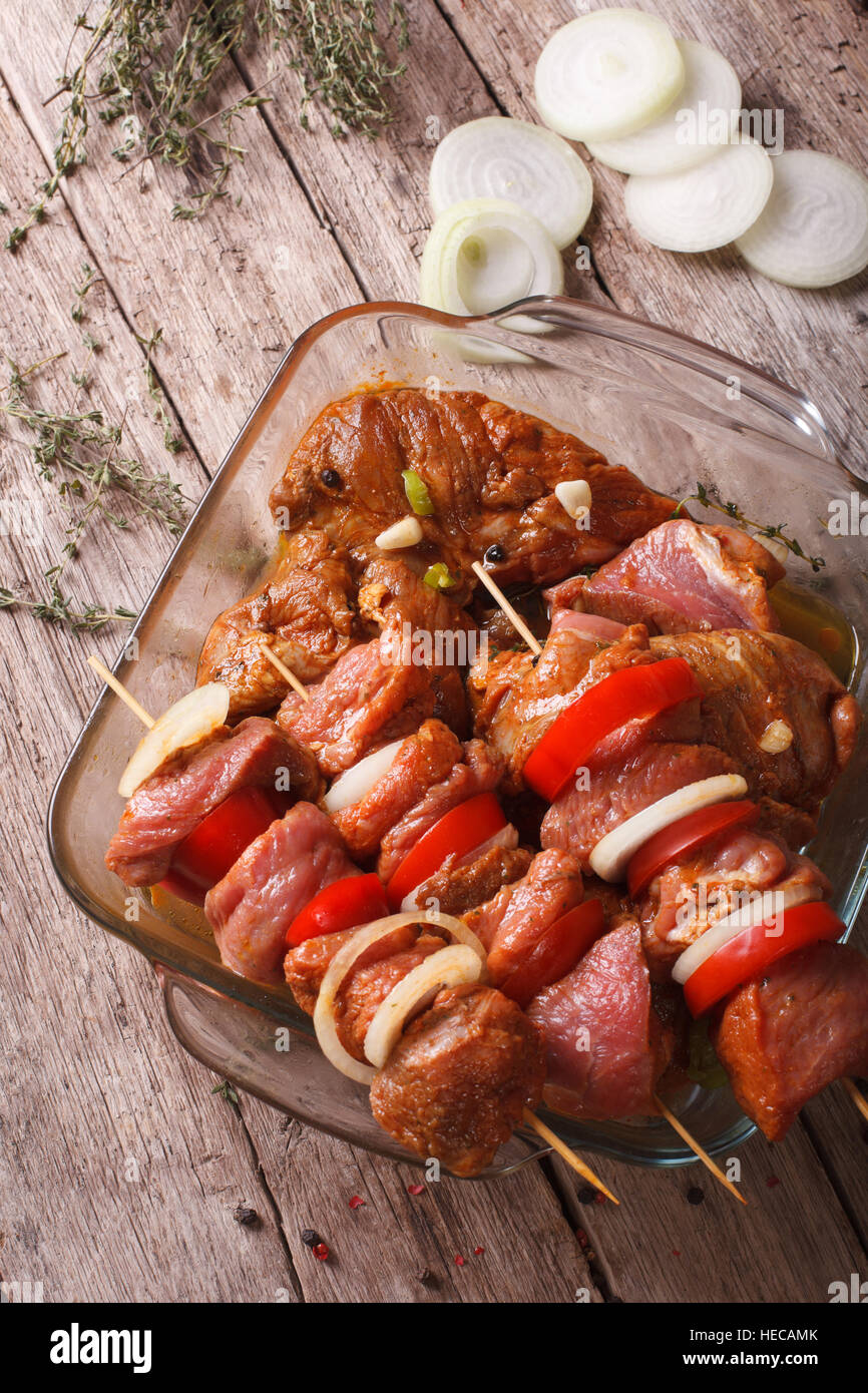 Raw kebab with vegetables in marinade on skewers closeup vertical