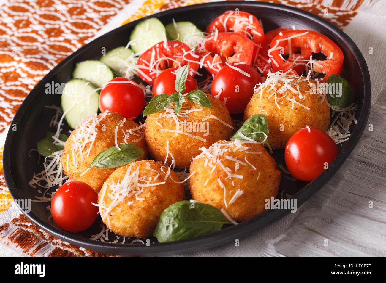 Fried arancini rice balls with parmesan and fresh vegetables on a plate