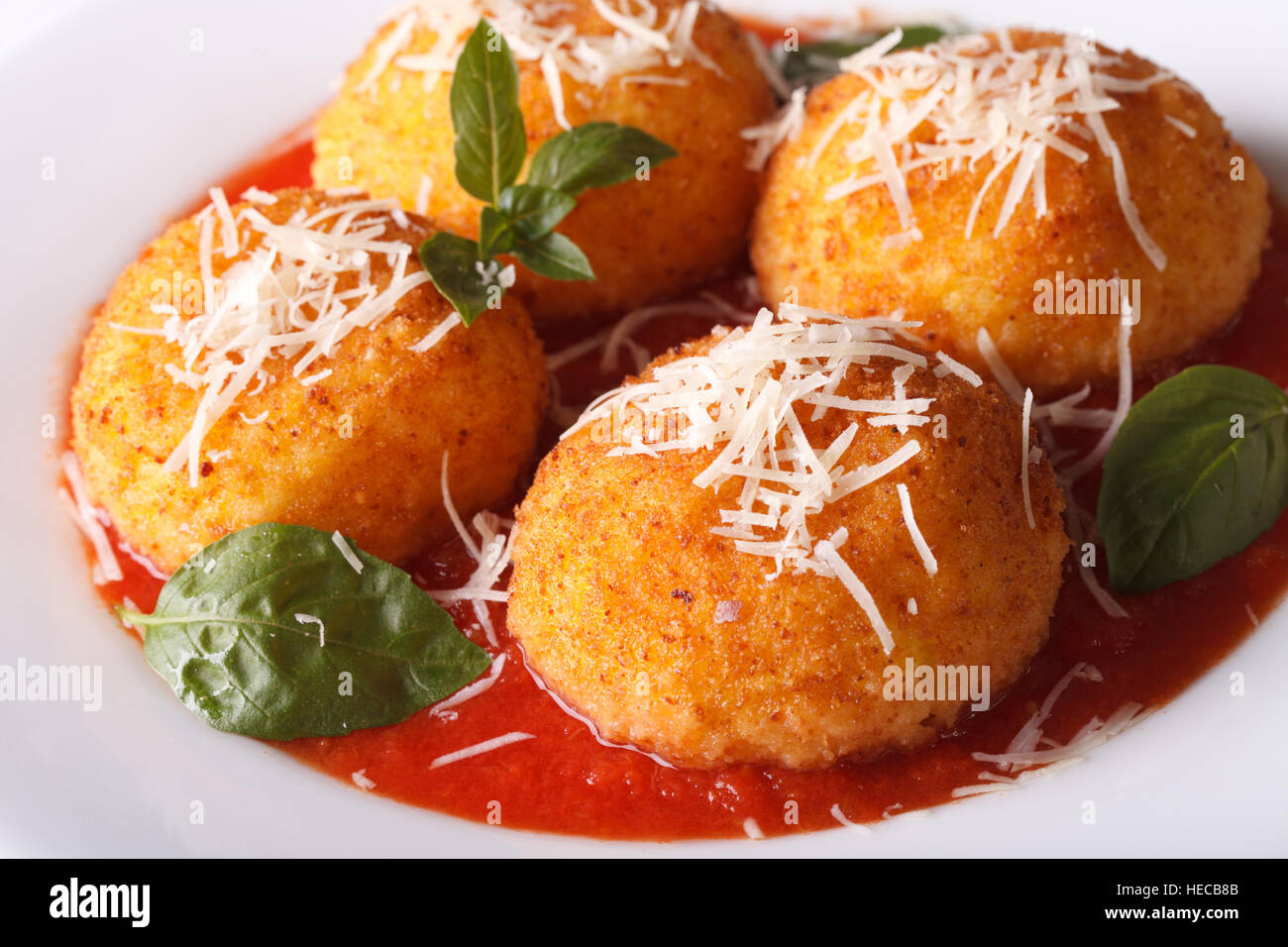 Italian arancini rice balls in tomato sauce on a plate closeup