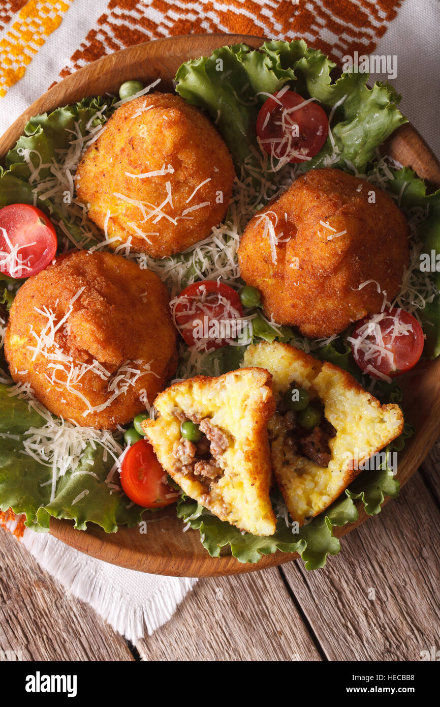 Arancini rice balls with meat and peas closeup on a plate. vertical