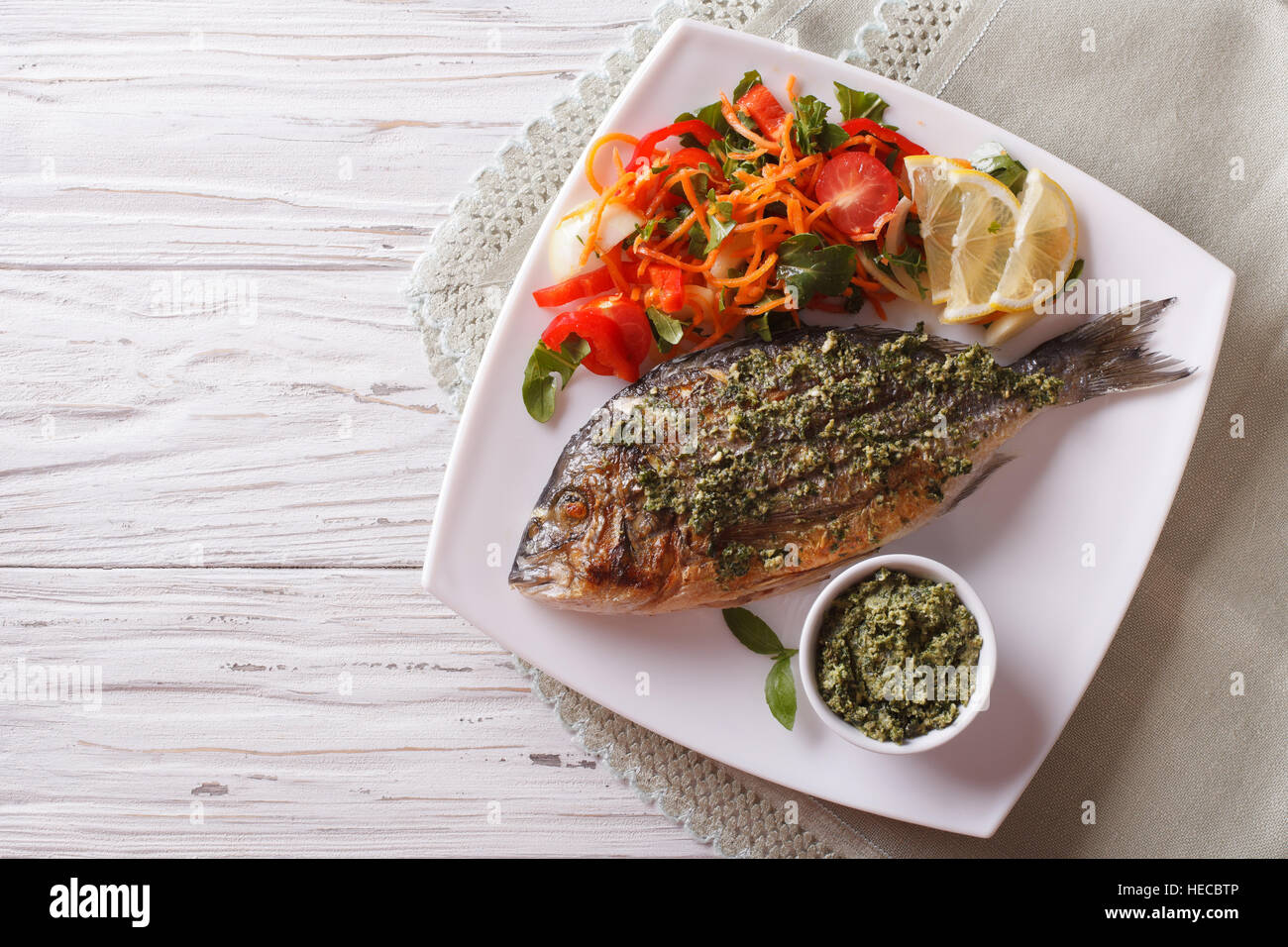 Grilled dorado fish with pesto and vegetable salad on a plate. horizontal top view Stock Photo