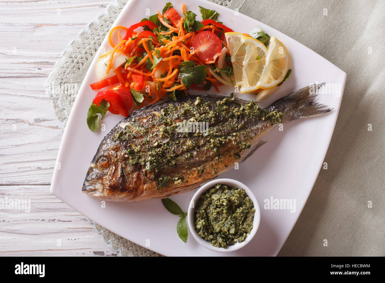 Grilled dorado fish with pesto and vegetable salad close-up on a plate. Horizonta top view Stock Photo