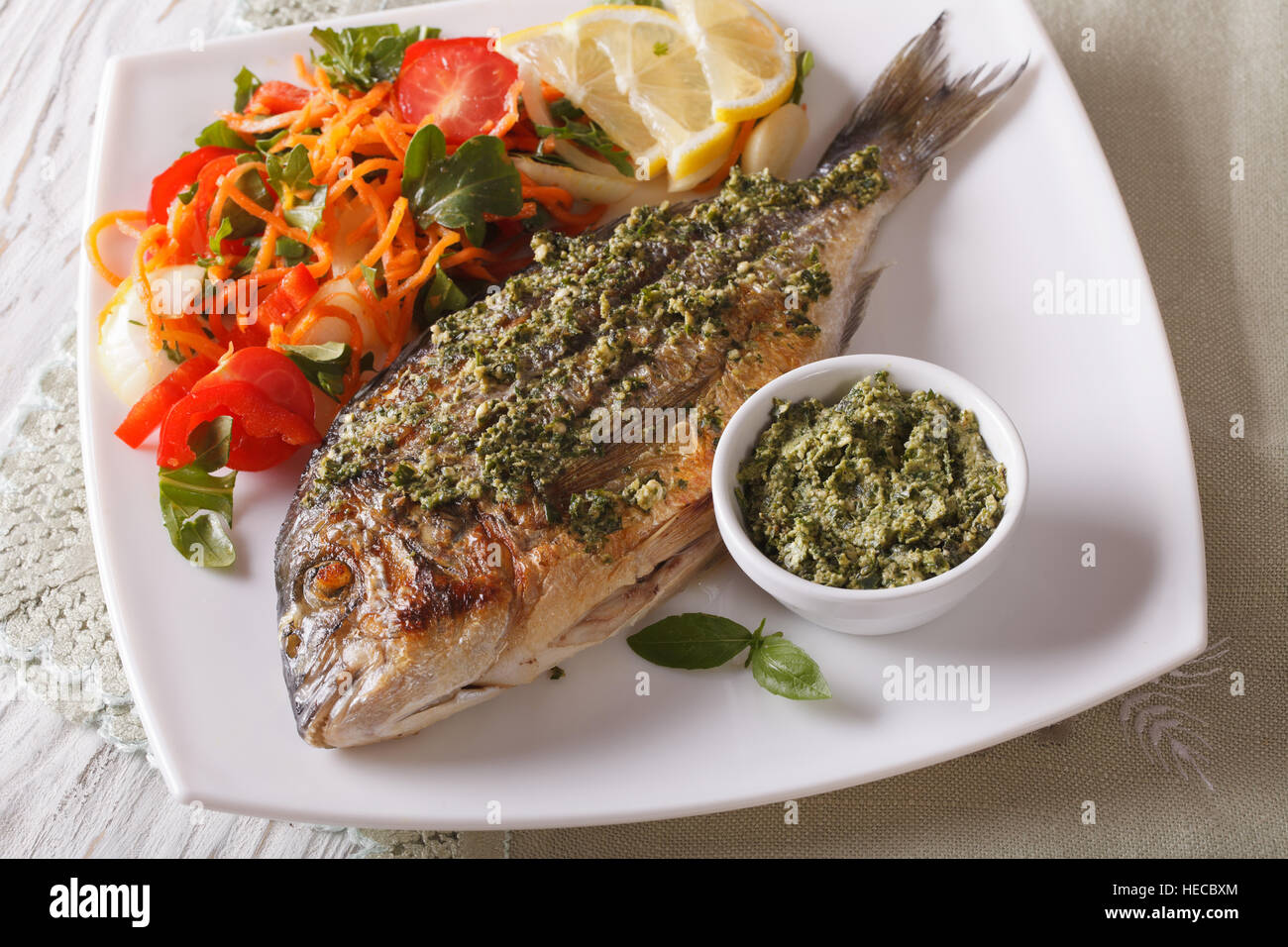 Grilled dorado fish with pesto and vegetable salad close-up on a plate. horizontal Stock Photo