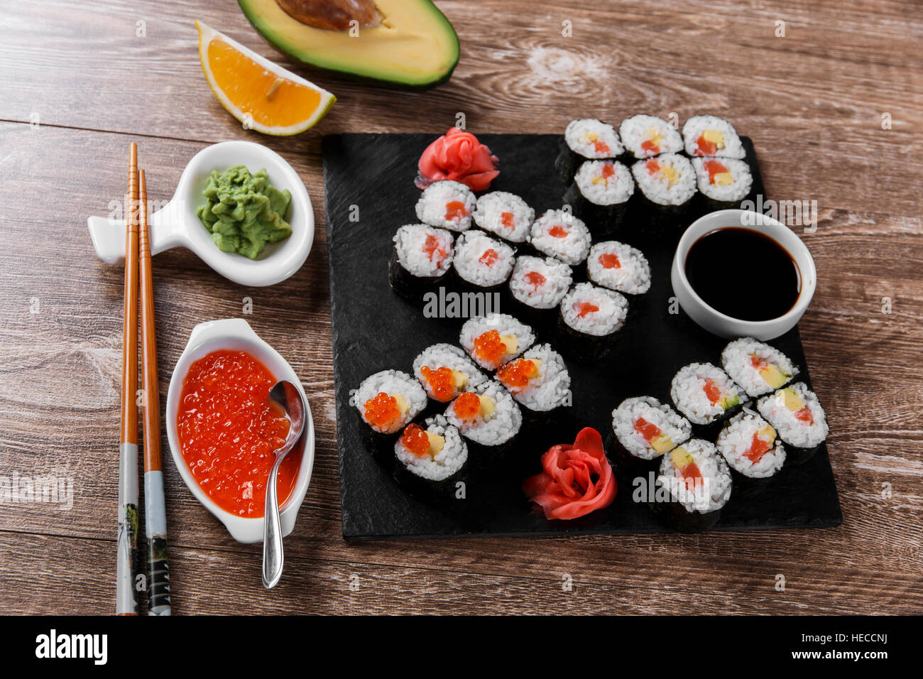 sushi rolls and ingredients served on a wooden surface Stock Photo