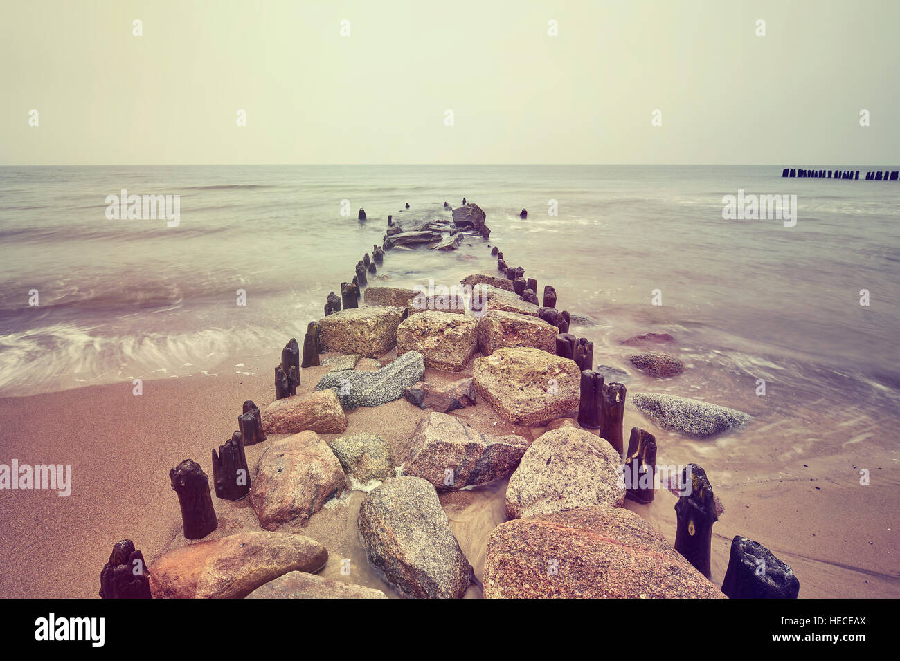 Vintage toned picture of an old breakwater on cloudy day. Stock Photo