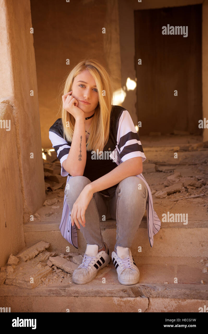 Blonde teenage girl in jeans and black tee-shirt in abandoned building. Stock Photo