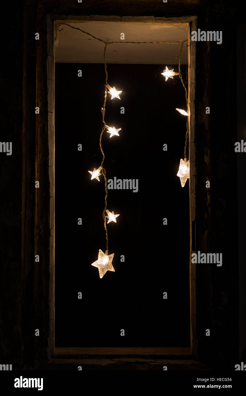 Christmas star lights in a house window at night. Tetbury