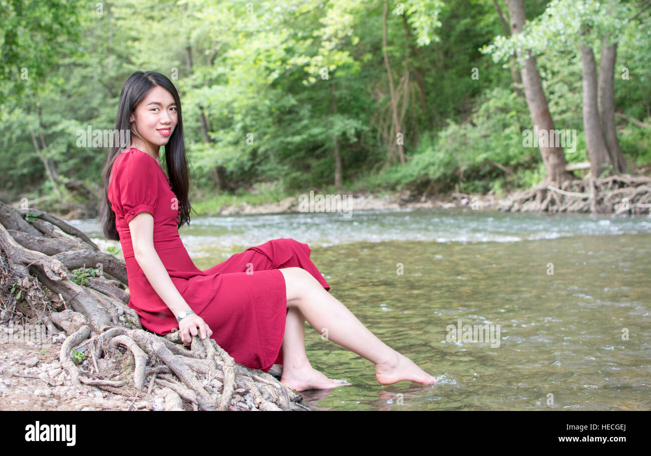 Fashionable woman sitting next to a river alone Stock Photo