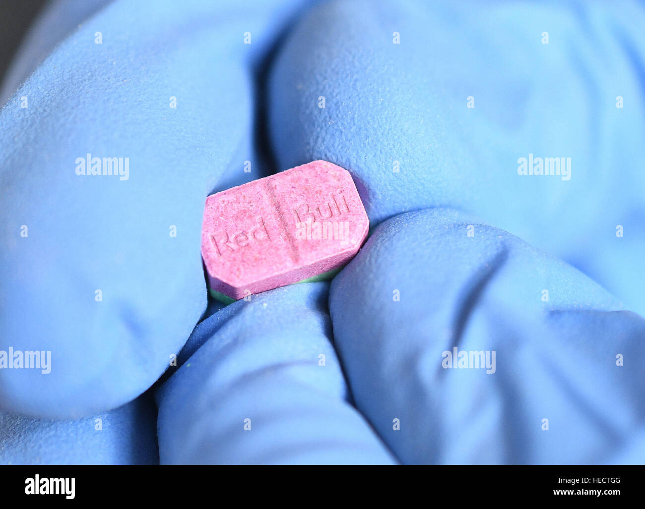 Cologne, Germany. 20th Dec, 2016. A customs officer presents an ecstasy pill at a press conference in Cologne, Germany, 20 December 2016. After several discoveries of large amounds of ecstasy between July and September, German customs presented the seized drugs Photo: Henning Kaiser/dpa/Alamy Live News Stock Photo