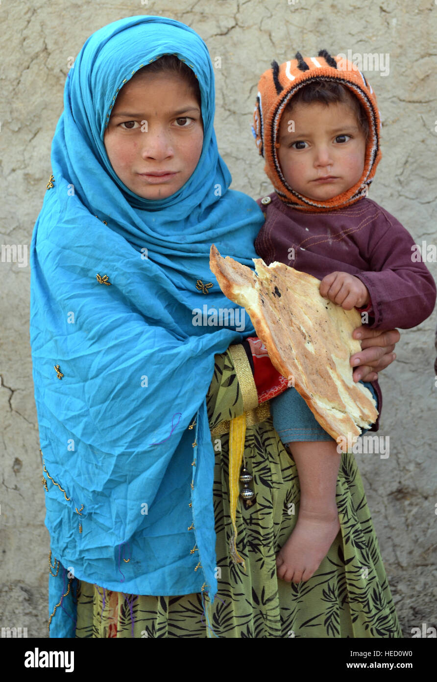 Small boy held by his sister in a small camp for internally displaced persons (IDP) on the outskirts of Kabul city, where mostly families from northern Kunduz and Baghlan live, in Afghanistan, 20 December 2016. Around 580,000 people have been displaced due to conflict-related violence in 2016 alone, surprising the Afghan government and international community alike. Photo: Mohammad Jawad/dpa Stock Photo