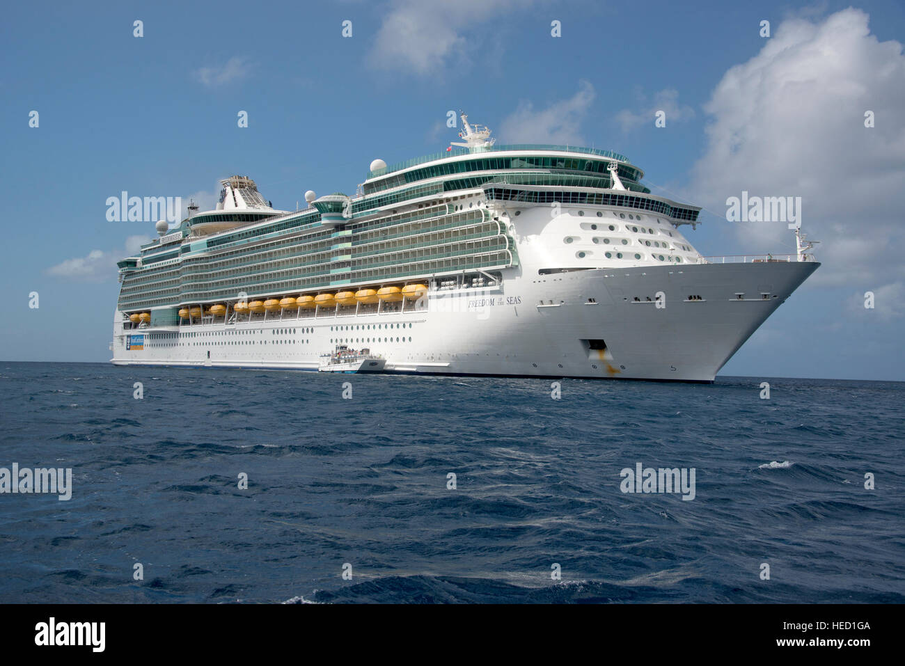 The Royal Caribbean Freedom of the Seas, which carries 4,515 passengers and 1,360 crew, and the Celebrity Reflection, which carries 3,609 passengers and 1271 crew, in the harbor of George Town, Grand Cayman in the Cayman Islands on Tuesday, December 20, 2016.  The smaller boat is a tender to ferry passengers back and forth to the island. Credit: Ron Sachs / CNP /MediaPunch Stock Photo