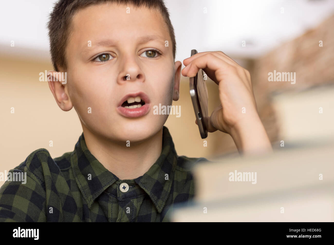 Young Boy Talking on Cell Phone at Home. Mobile Phone Talk Concept. Stock Photo