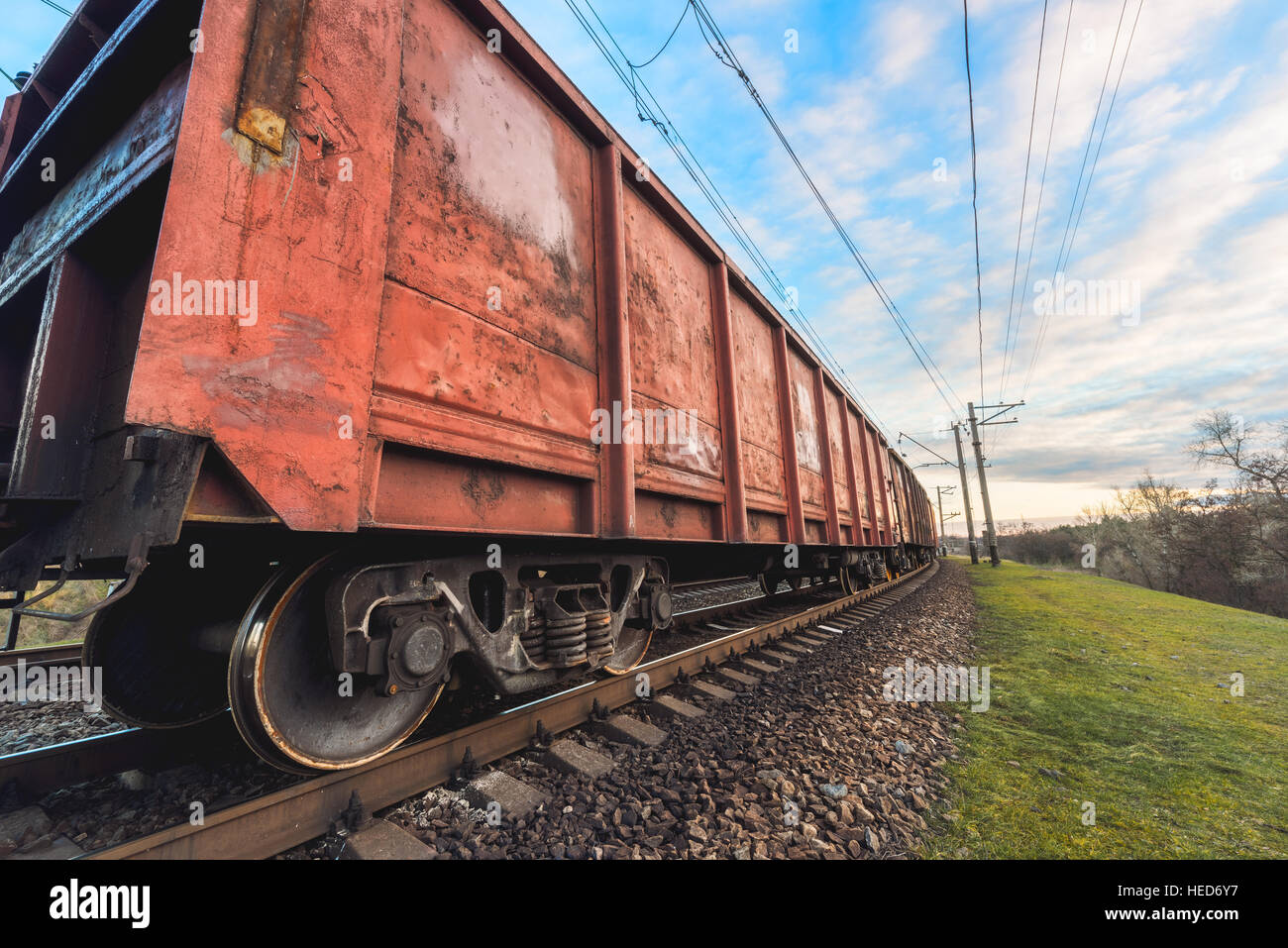 Railway station with cargo wagons and train against beautiful cloudy sky at sunset. Colorful industrial landscape. Railroad Stock Photo