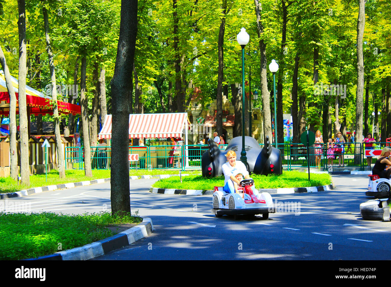 children with their parents drive the electric cars in Gorky park in Kharkiv Stock Photo