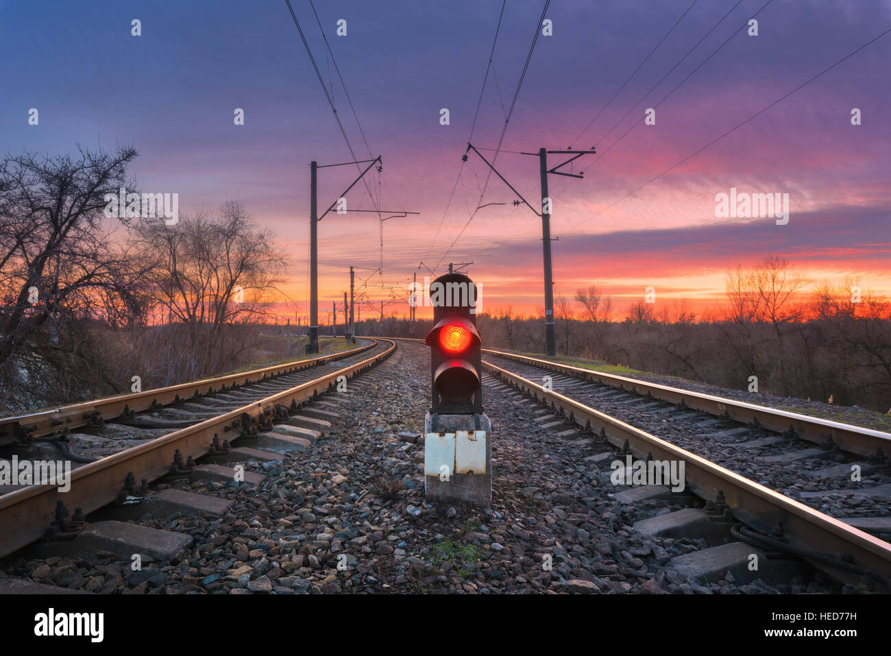 Railway station with semaphore against beautiful sky with clouds at sunset. Colorful industrial landscape. Railroad Stock Photo
