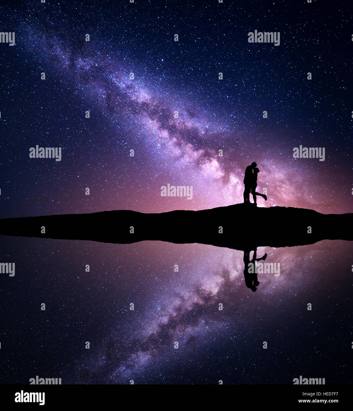 Milky Way. Night landscape with silhouettes of hugging and kissing man and woman on the mountain near the river. Starry sky Stock Photo
