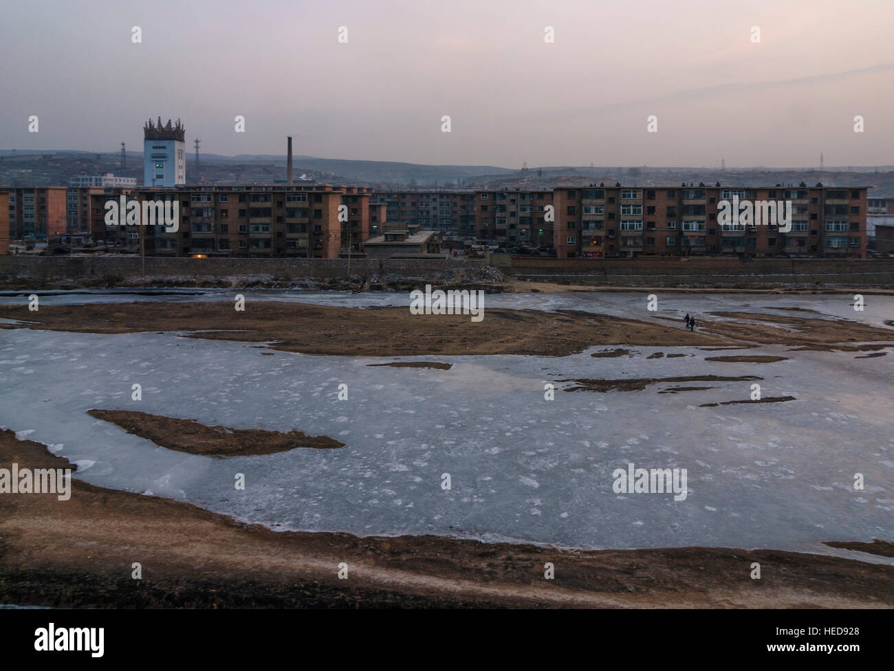 Datong: Datong coal mine; Conveyor tower and residential buildings on a frozen river, Shanxi, China Stock Photo