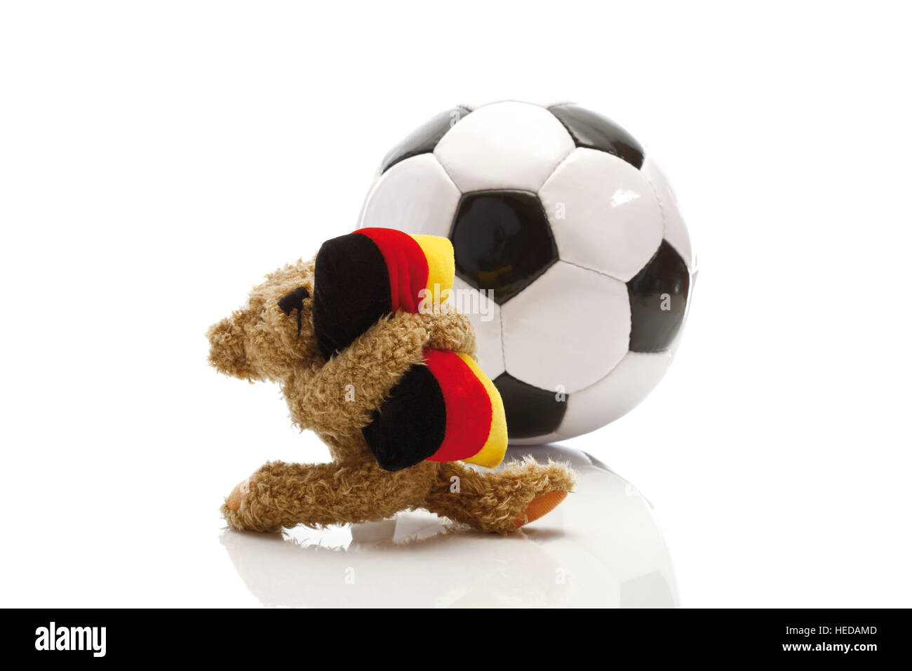 Teddy bear holding a cushion in the colours of the German flag standing