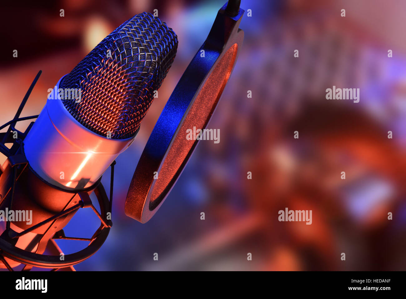 Studio microphone with headphones and mixer background with blue and red lights live production. Elevated view Stock Photo