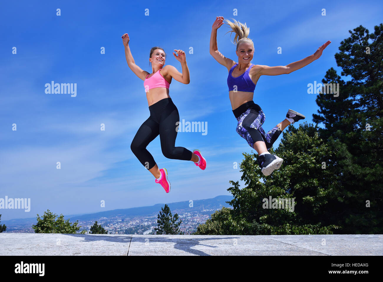 Two happiness young women jumping over blue sky Stock Photo - Alamy