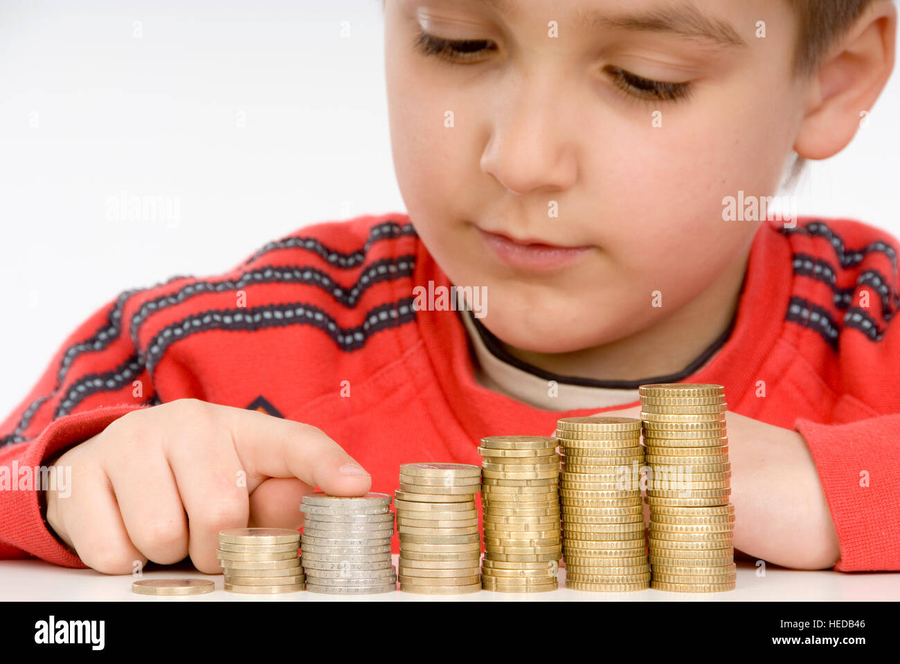 7 year-old boy counting stacks of coins, stacking coins Stock Photo - Alamy