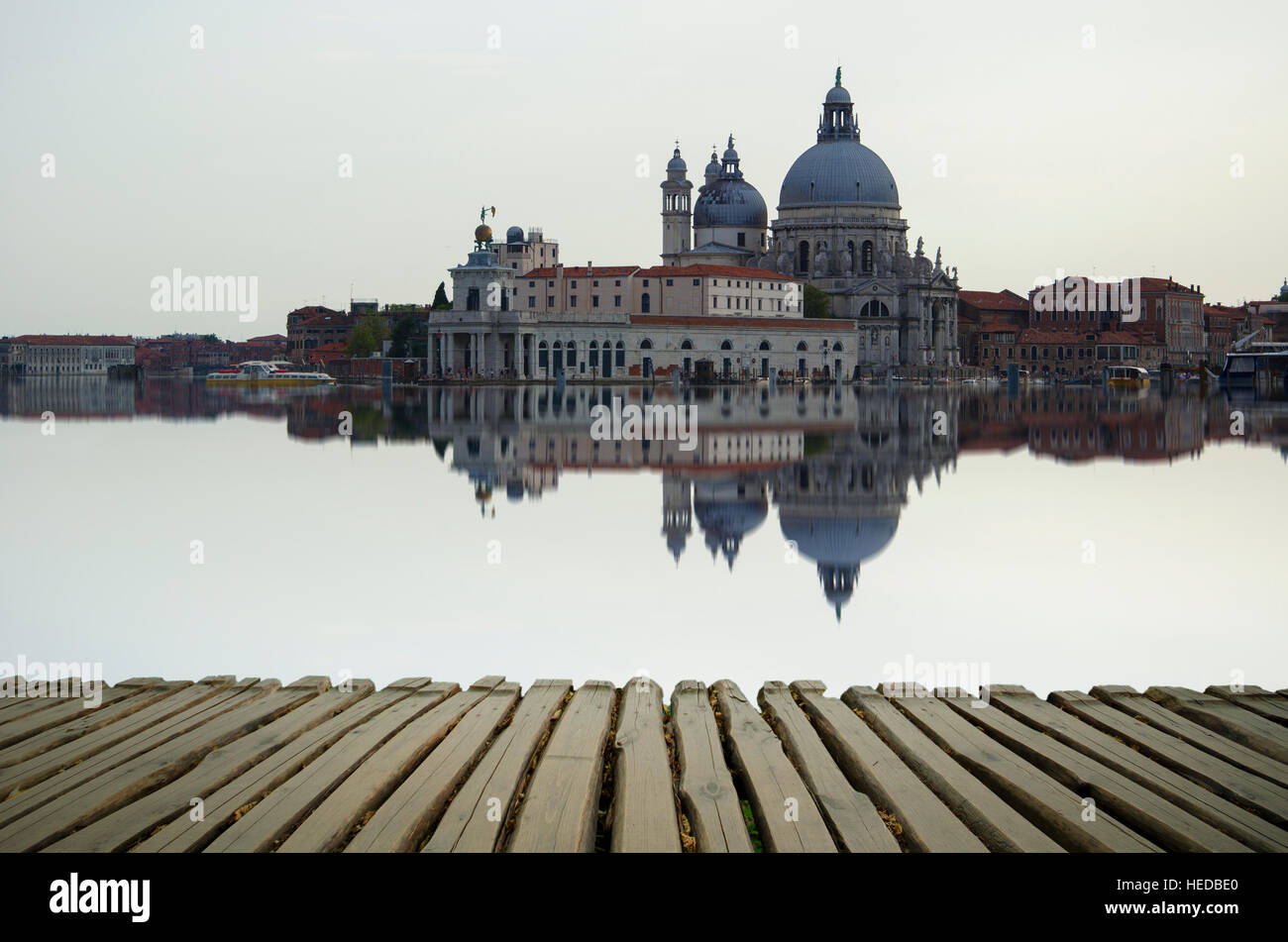 Fine art image with Grand Canal and Basilica Santa Maria della Salute, reflected on the water surface, with wood planks floor fo Stock Photo